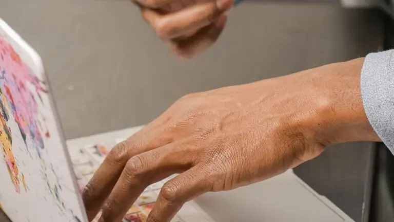 Person holding a bank card beside an online laptop screen