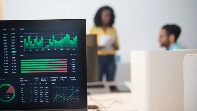 Office team discussing data displayed across screens
